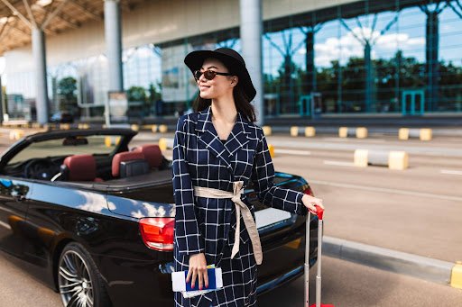 From Runway to Road Trip Woman with luggage arriving at an airport for a Central Andros car rental trip Woman with luggage beside a rental car at an airport for a Central Andros road trip